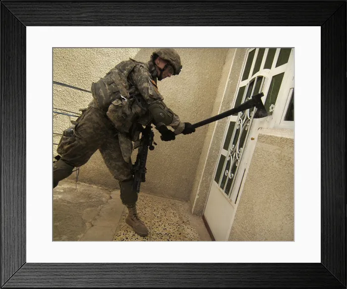 Framed Print : US soldier breaks down a door during a house-to-house search for illegal weapons and explosives in the Sadiyah section of Baghdad Iraq. May 6 2007. (BSLOC_2011_12_144)