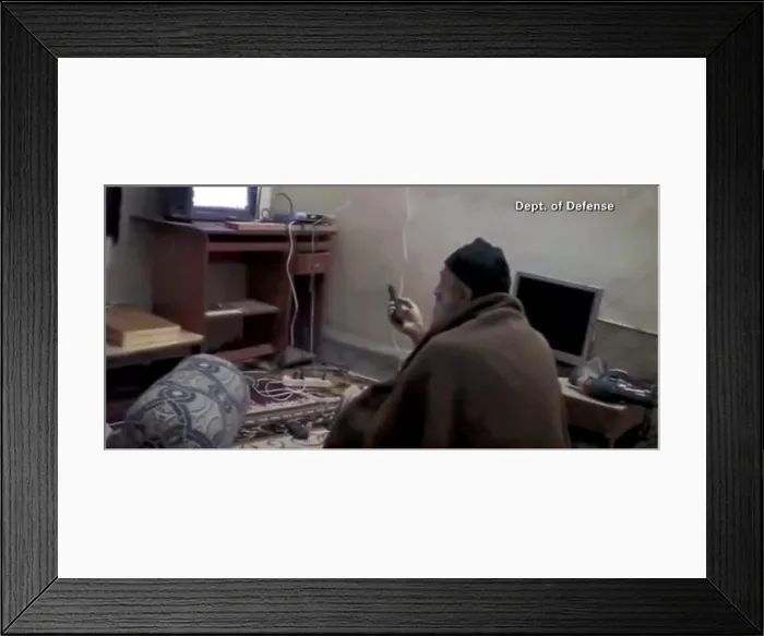 Framed Print : Video still of Al Qaeda Terrorist leader Osama Bin Laden with remote control in hand while viewing himself on television