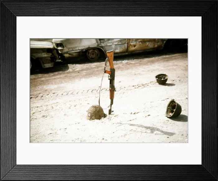 Framed Print : Discarded Iraqi helmets scattered around a Kalashnikov assault rifle near vehicles destroyed by Coalition forces during Operation Desert Storm. Mar. 1 1991 (BSLOC_2011_12_8)