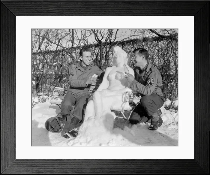 Framed Print : Two U.S. soldiers offer Agnes their snow woman, Camel cigarettes and a Coke. European theater. Jan. 14, 1945. World War 2. (BSLOC_2014_8_101)