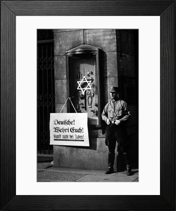 Framed Print : Anti-Semitic boycott in Berlin, Germany, April 1, 1933. A Nazi storm trooper stands beside a placard reading, Germans, defend yourselves, do not buy from Jews