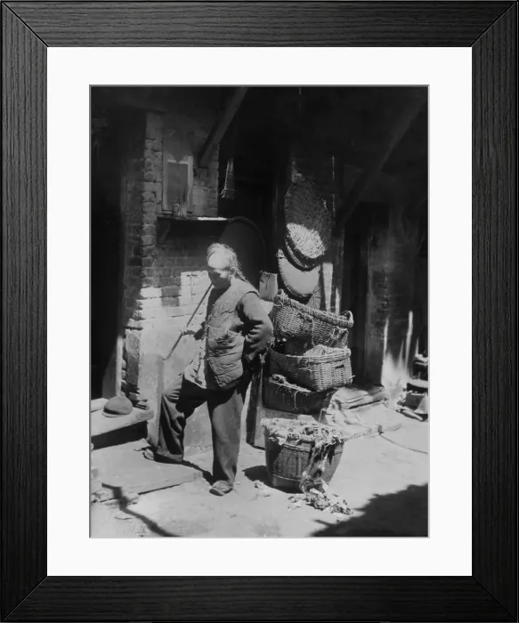 Framed Print : Chinese man smoking long pipe in Rag Pickers Alley, San Francisco, California, c. 1921. Nearby is a basket of fabric fragments, collected for salvage and reuse (BSLOC_2018_1_44) Framed Print : Chinese man smoking long pipe in Rag Pickers Alley, San Francisco, California, c. 1921. Nearby is a basket of fabric fragments, collected for salvage and reuse (BSLOC_2018_1_44)