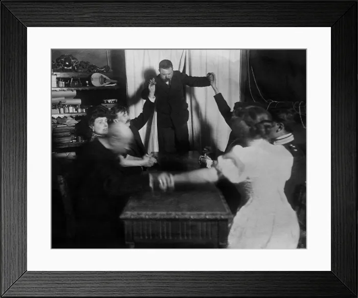 Framed Print : Man levitates during a sance at Baron von Erhardts Rome studio, 1909. Eight men and women hold hands while seated around a table