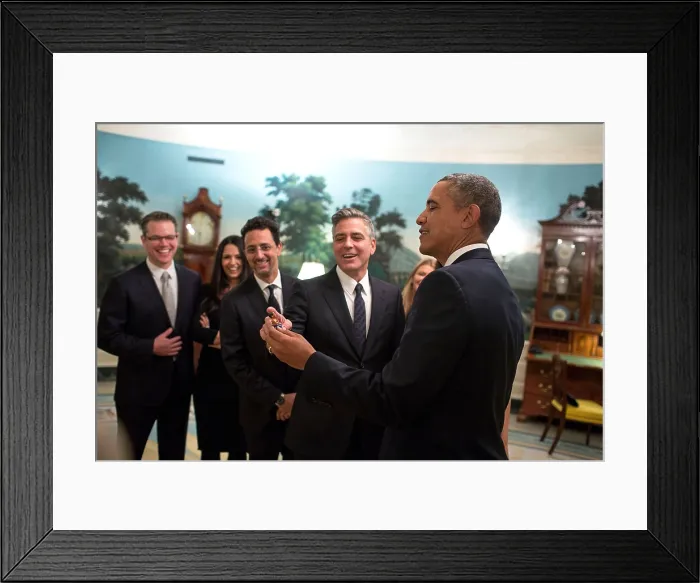 Framed Print : President Barack Obama jokes with cast members of the movie The Monuments Men'. The President appears to be holding a tiny Obama Doll