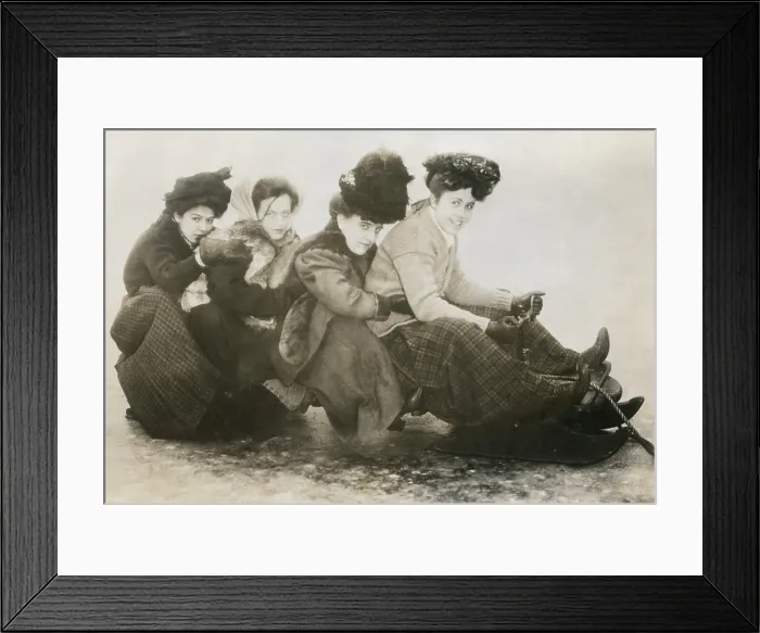 Framed Print : Four young American women on a sled, c. 1910. The huddled young girls wear layers of fur, wool, and leather winter clothing (BSLOC_2018_4_207)