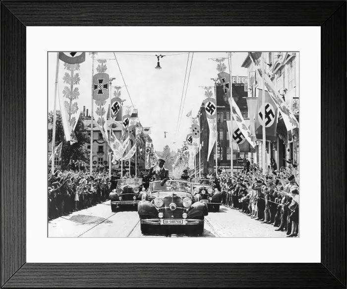 Framed Print : Adolf Hitler waving to crowds from his car at the head of a parade. The streets are decorated with various swastika banners. Ca. 1934-38. Location is unidentified Framed Print : Adolf Hitler waving to crowds from his car at the head of a parade. The streets are decorated with various swastika banners. Ca. 1934-38. Location is unidentified