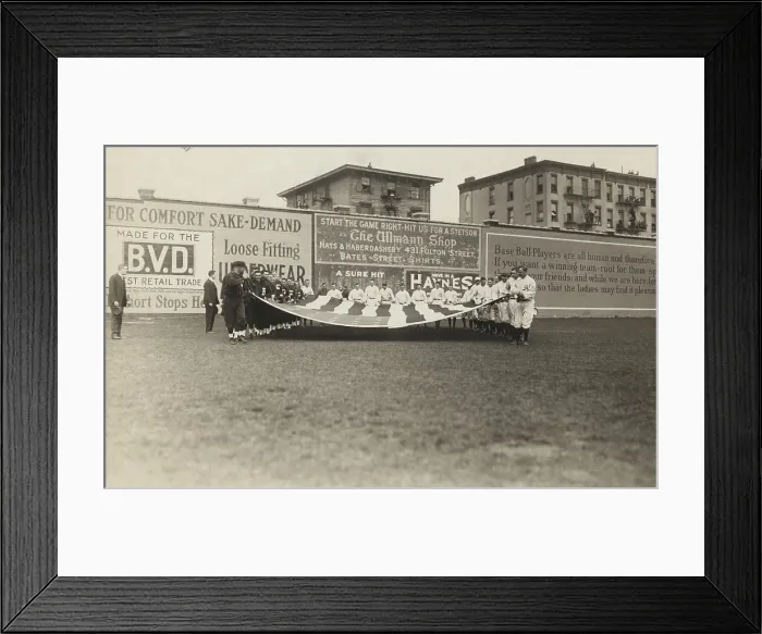 Framed Print : Buffalo Bisons and Brooklyn Tip Tops baseball players holding a large American flag, 1914. The first singing of THE STAR SPANGELED BANNER at a baseball game occurred in 1887
