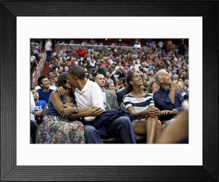 Framed Print : President Barack Obama kisses First Lady Michelle Obama for the Kiss Cam'. Malia and Joe Biden watch the kiss on Jumbotron screens the Verizon Center in Washington, D.C