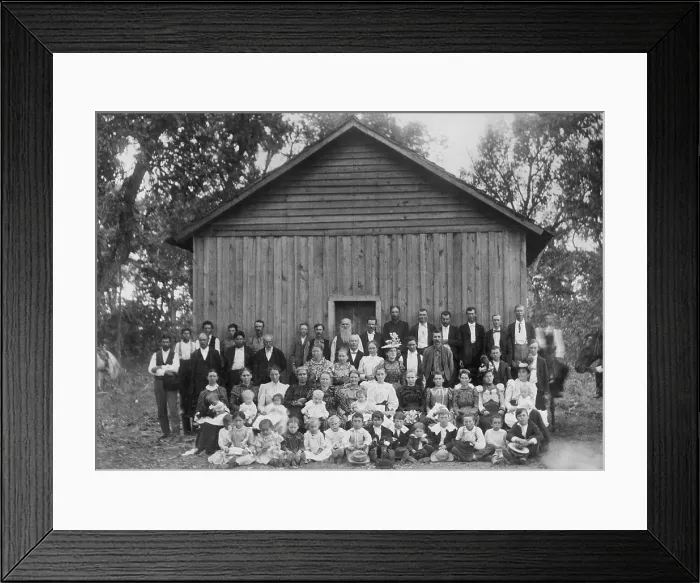 Framed Print : Euro-Americans and Native Americans pose for a Sunday school portrait. Adults, teenagers, and children are dressed in their best clothes by a large, simple, wood building