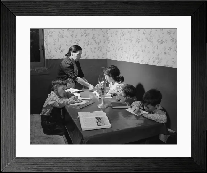 Framed Print : Mrs. Maclovia Lopez, a bilingual Spanish-American mother, supervises her children's homework in their Trampas, New Mexico home. 1943 photograph by John Collier