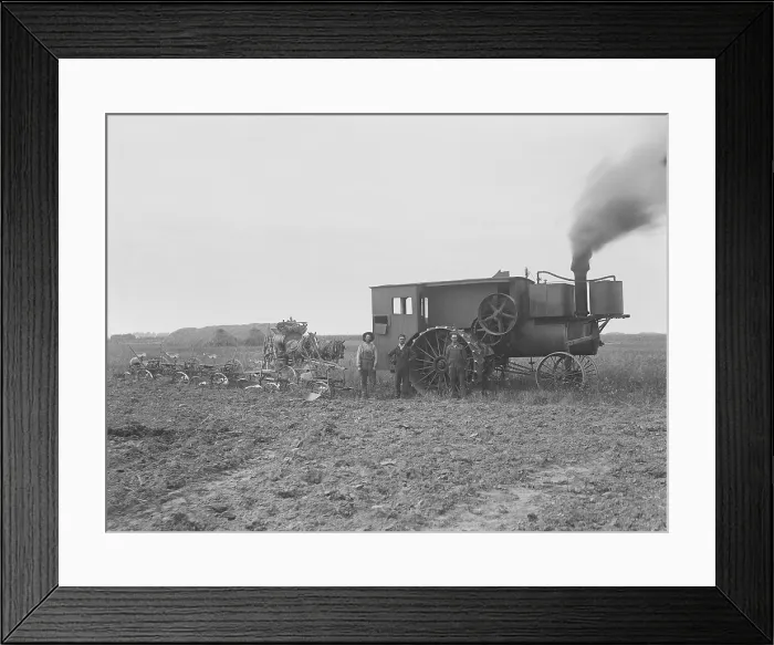 Framed Print : Three farmers stand by a huge steam tractor attached to six combined, stone weighted, plows, 1901. The land in the foreground is already plowed