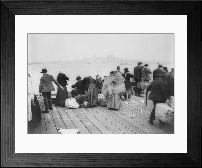 Framed Print : Immigrants waiting to be transferred by Ferry from Ellis Island, on October 30, 1912. In the background is the skyline of downtown Manhattan