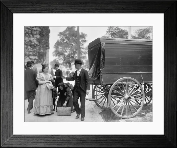 Framed Print : Two women immigrants and a child engage a wagon for transport to their next stop, probably a boarding house or railroad station