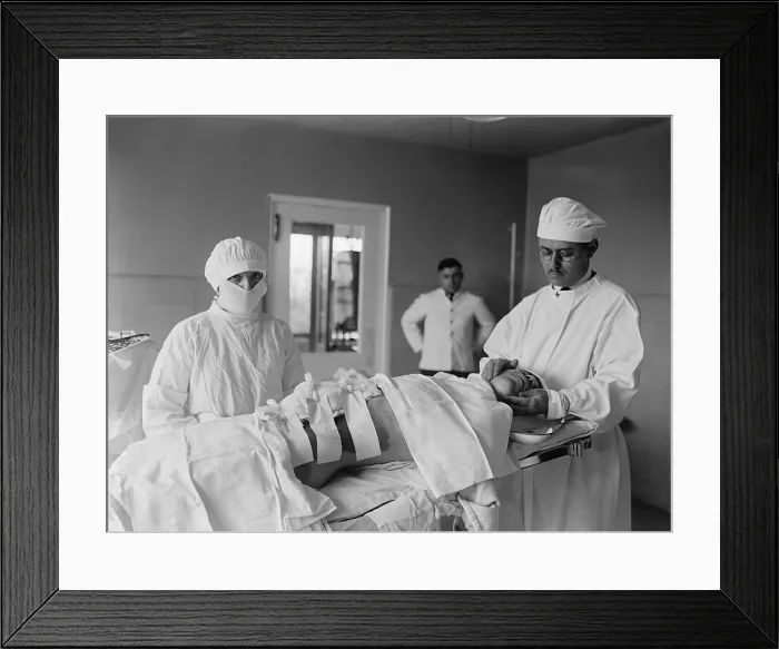 Framed Print : Anesthesiologist and surgical nurse with a post-operative patient. A large bandage covers the incision, and skin is stained by antiseptic solution