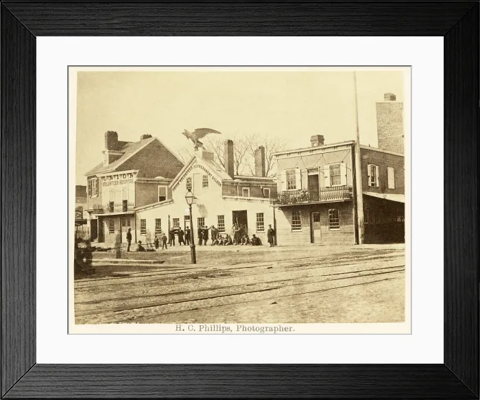 Framed Print : Philadelphia in the 1860s. Street scene with men gathered at the giant eagle adorned Union Volunteer Refreshment Saloon next to the Union Volunteer Hospital