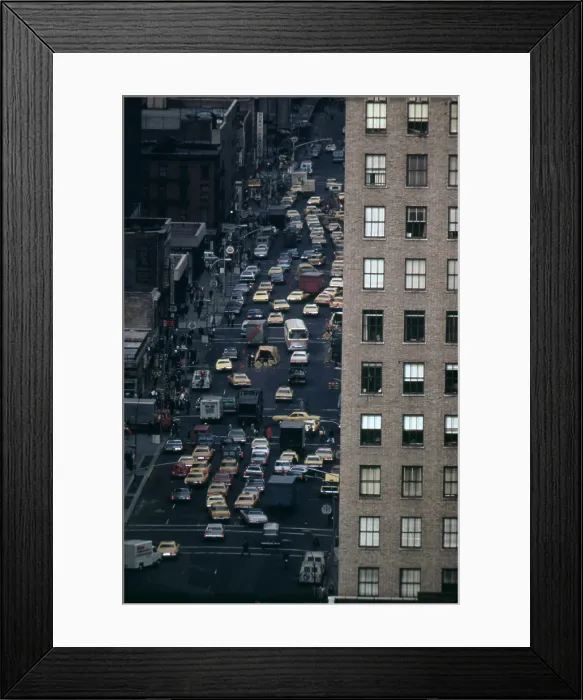 Framed Print : Traffic in New York City. View of vehicles on Manhattan's Sixth Avenue at 42nd Street is framed by a massive pre-war apartment building. Ca. 1973-75
