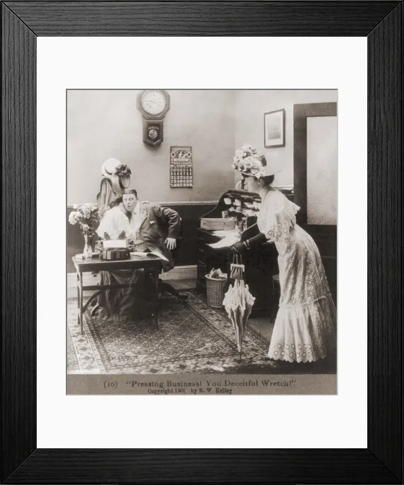Framed Print : PRESSING BUSINESS YOU DECIETFUL WRETCH Is the caption to a photo of a woman surprising husband who is embracing secretary in his office. Ca. 1907. (BSLOC_2010_18_88)