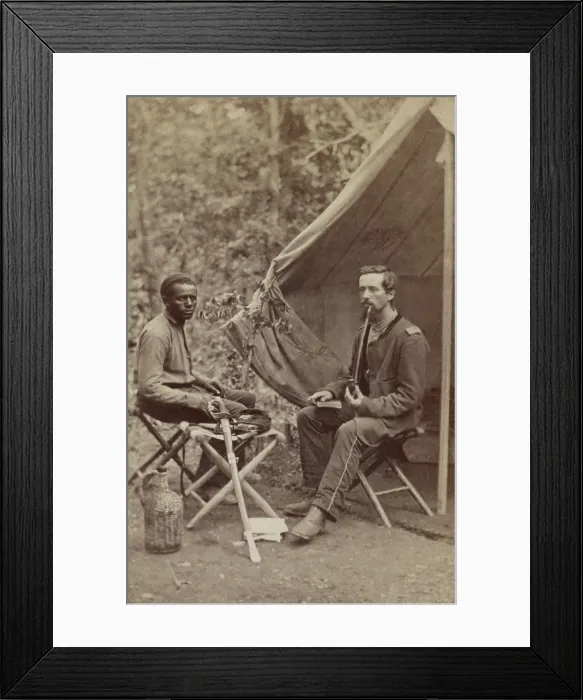 Framed Print : Civil War Union officer of 23d New York Infantry smoking a long stem pipe outside his tent, 1861-1863. An African American in civilian clothes sits nearby