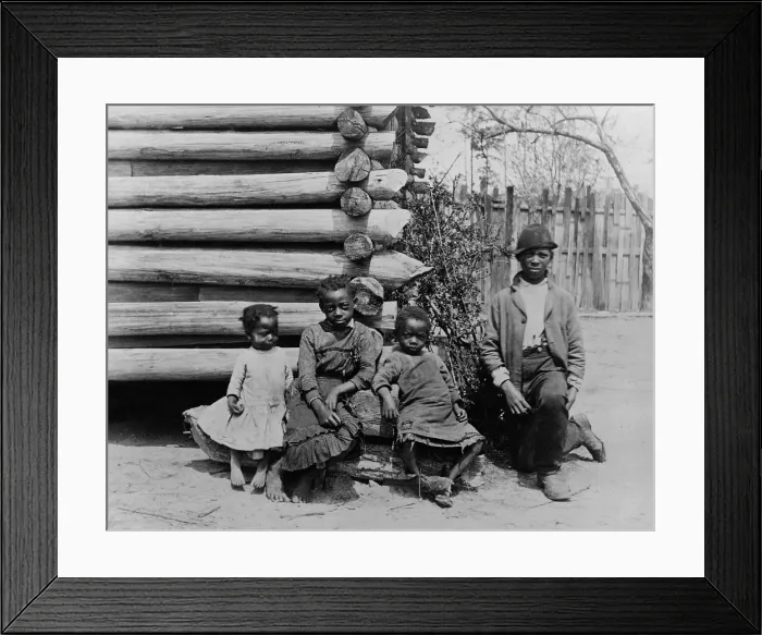 Framed Print : African American teenager and three children posed by log building. Photo was taken near Thomasville, Georgia, between 1884-91, by Philadelphia physician Joseph John Kirkbride