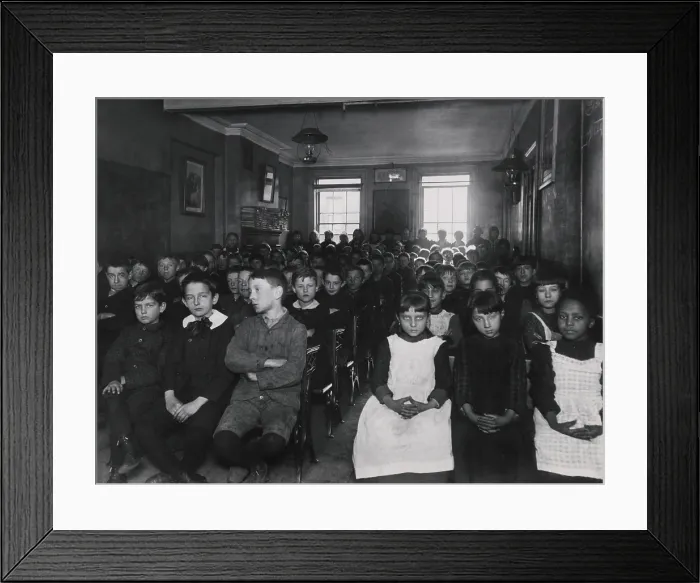 Framed Print : About 75 children packed into a NYC classroom in New York City, c. 1890. The girls are separated from boys, but all sit in chairs without desks