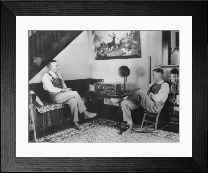 Framed Print : Middle aged farmer and his adult son listening to the radio in their comfortable home, c. 1925