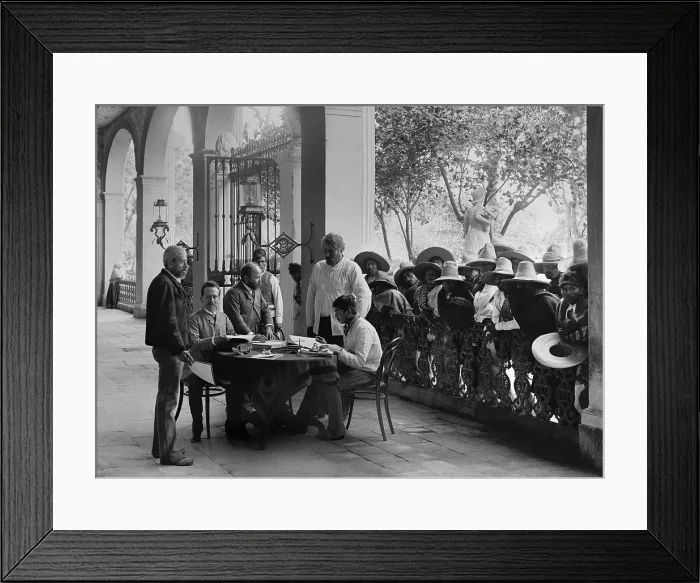 Framed Print : European-Mexican administrator sits in a Hacienda porch, San Luis Potosi, Mexico, c. 1890. Landless mestizo peons wait their turn for an audience with the plantation manager