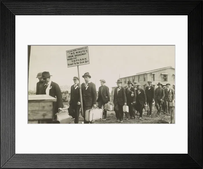Framed Print : Young men in civilian clothes arriving for military service at Camp Upton, Long Island, NYS. One carries a sign: From New Rochelle, 45 minutes from Broadway, bound for Yaphank