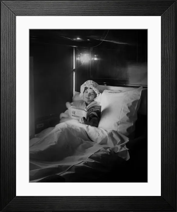 Framed Print : Woman reads in an electric-lighted berth on a deluxe overland express train, c. 1915-1919