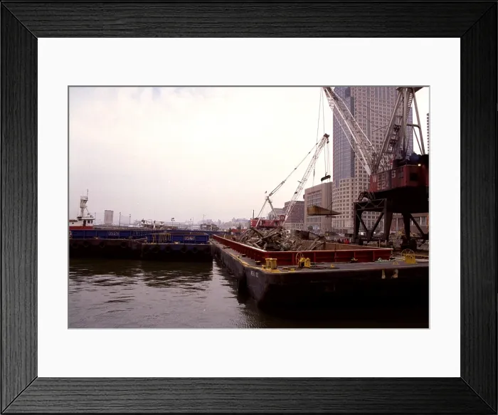 Framed Print : A few blocks from Ground Zero heavy cranes place World Trade Center wreckage into barges for transport to the Fresh Kill Landfill on Staten Island. March 15 2002