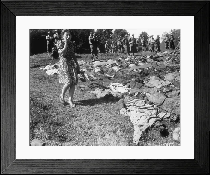Framed Print : A German women walks past the exhumed bodies of some of the 800 slave workers. They were murdered by SS guards at Flossenburg concentration camp near Namering, Germany. U.S Framed Print : A German women walks past the exhumed bodies of some of the 800 slave workers. They were murdered by SS guards at Flossenburg concentration camp near Namering, Germany. U.S