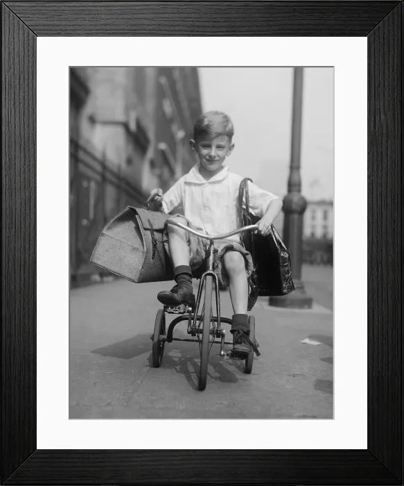 Framed Print : Youngster rides his tricycle on the sidewalks of New York City, c. 1920. He is transporting two packages from the local grocery store (BSLOC_2016_8_85) Framed Print : Youngster rides his tricycle on the sidewalks of New York City, c. 1920. He is transporting two packages from the local grocery store (BSLOC_2016_8_85)