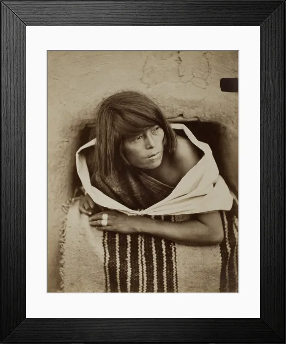 Framed Print : ZUNI, WATCHING, c. 1879-81, by John K. Hillers. A Zuni woman leans out of an adobe window, with her shoulders encircled by loose textile garments