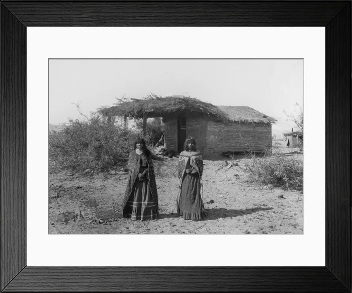 Framed Print : Two Mojave Indians girls stand in front of a small wattle and daub dwelling with a thatched roof, 1900, in this photo by Charles C. Pierce