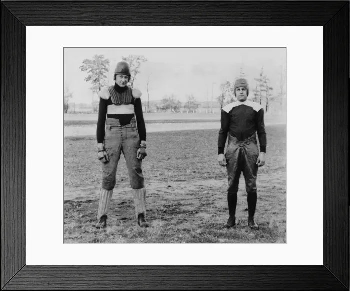 Framed Print : Notre Dame University football players wearing old and new football uniforms. At left is a football suit of the 1880's with external padding