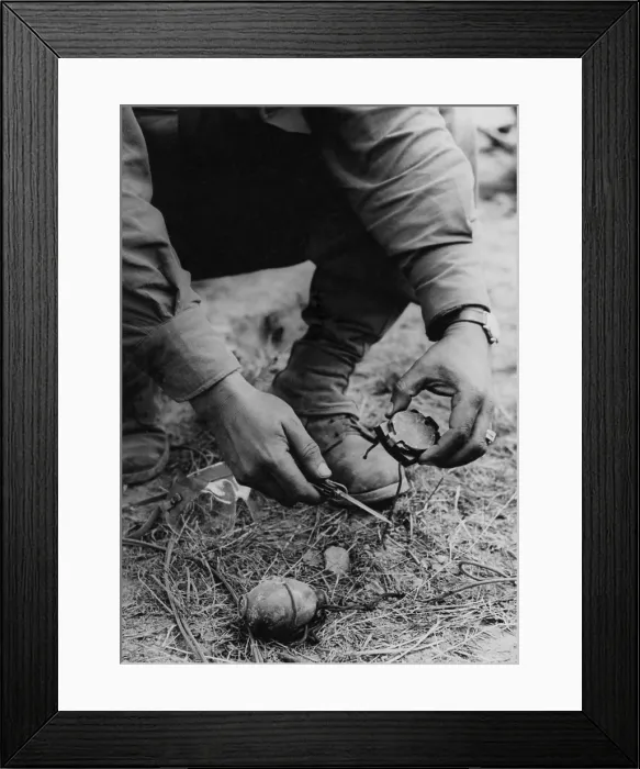 Framed Print : U.S. soldier dismantles a German booby trap planted on the road to St. Gilles. The device consisted of a tempting compass attached to a grenade with a shoestring