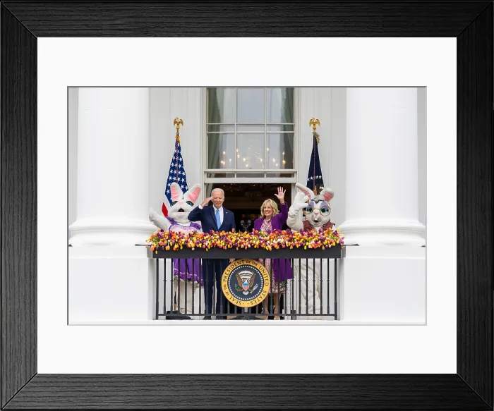 Framed Print : In a ceremony challenging Presidential dignity, Joe Biden salutes, as the First Lady Jill Biden and two giant Easter Bunnies wave from a White House balcony, April 18, 2022