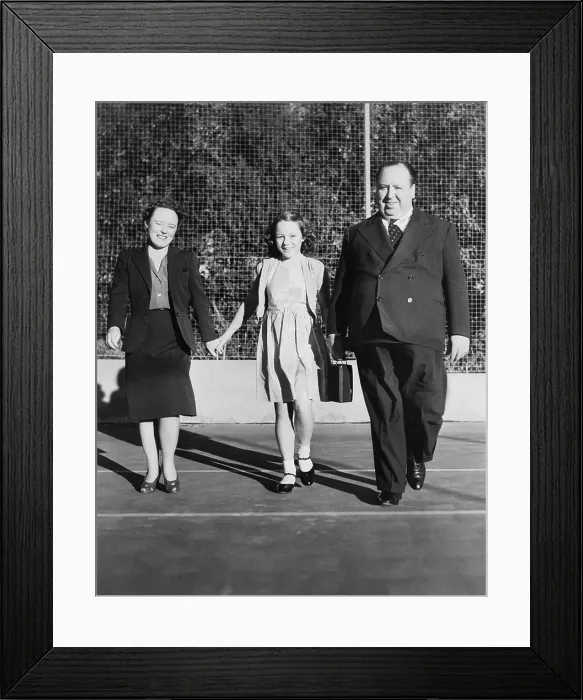 Framed Print : Alfred Hitchcock strolling about the grounds of his Bel Air estate. He is with his wife, Alma Reville, and his daughter, Patricia. Ca. 1942 - (BSLOC_2014_17_79)