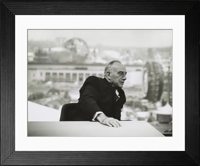 Framed Print : Robert Moses in 1964, seated at a table with a view of the New York Worlds Fair in the distance
