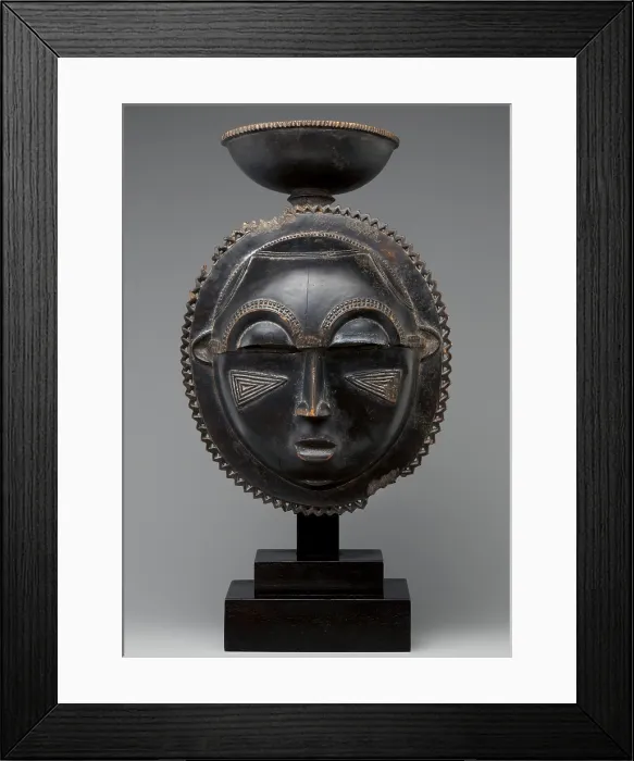 Framed Print : MOON MASK, 1880s, Baule peoples, Ivory Coast, Africa, sculpture, wood. Round wooden mask has a oval face edged by a zigzag border and topped with a cup