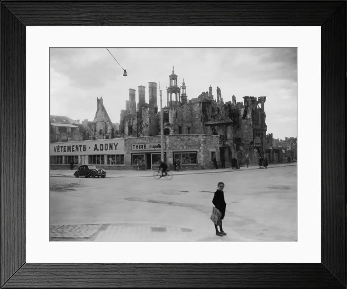 Framed Print : World War 2 destruction and Post war reconstruction in Caen, France. The ruins of homes and a church remain behind stores newly constructed from salvaged materials. 1946