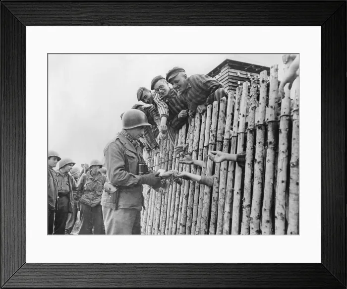 Framed Print : GI of the Seventh US Army gives his last cigarettes to liberated Dachau prisoners behind a stockade. April 29, 1945, World War 2 (BSLOC_2015_13_21) Framed Print : GI of the Seventh US Army gives his last cigarettes to liberated Dachau prisoners behind a stockade. April 29, 1945, World War 2 (BSLOC_2015_13_21)