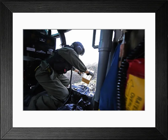 Framed Print : US Coast Guard helicopter drops a box of MRE's to locals near Utuado, Puerto Rico. The community was stranded after Hurricane Maria by washed out roads and mudslides, Oct