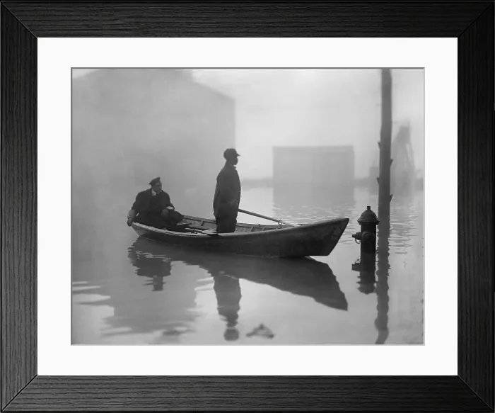 Framed Print : An African American steers a boat through Georgetown, during a Potomac River flood 1910-09. His seated passenger wears a uniform (BSLOC_2017_17_93)