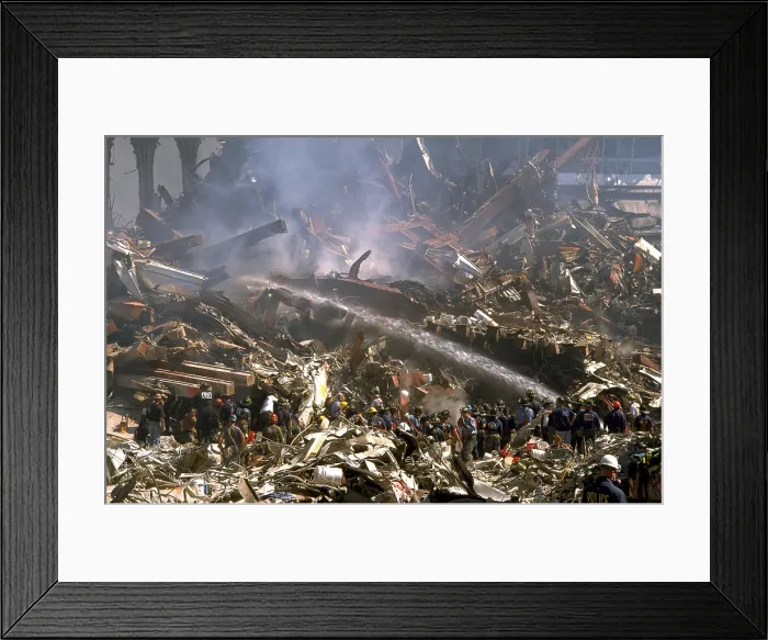 Framed Print : Firemen sprays still burning ruins of the World Trade Center on Sept 16, 2001. In upper right are ruins of WTC 3, the Marriott World Trade Center, once a 22 story hotel