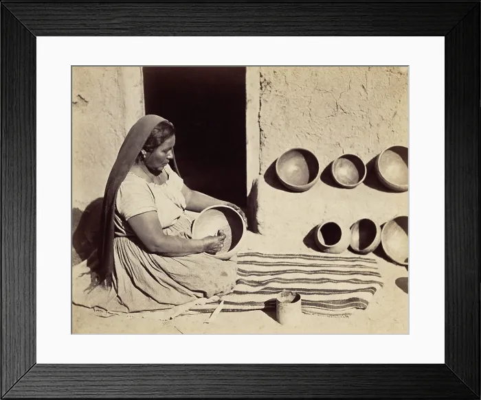 Framed Print : A Pueblo Indian woman polishes a pottery bowl in a doorway. 1879 photograph by John K. Hillers