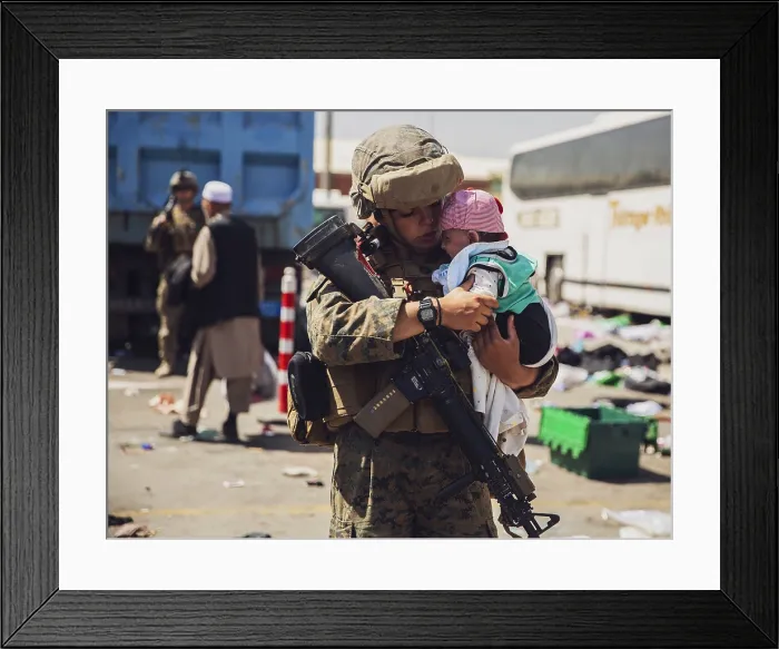 Framed Print : A US Marine holds a baby while its family is cleared for during the non-combatant evacuation operation at Kabul, Afghanistan, Aug. 28, 2021 (BSLOC_2021_14_43)