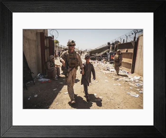 Framed Print : US Marine escorts an Afghan youth to his family through a fortified enclosure during the evacuation operation at Kabul airport, Afghanistan, Aug. 24, 2021 (BSLOC_2021_14_44)