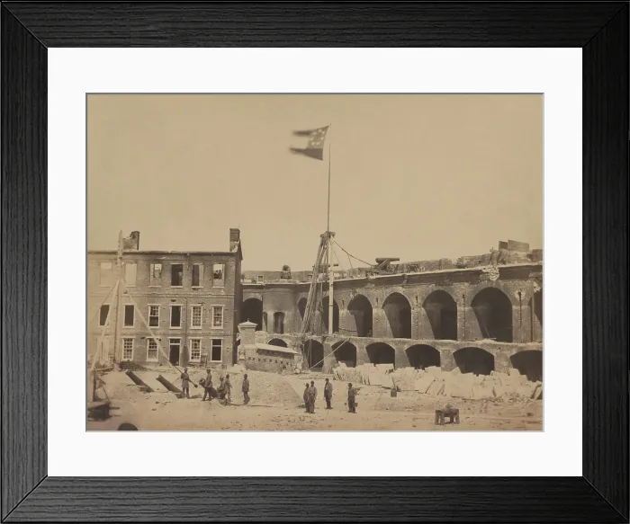 Framed Print : Confederate flag flying over the ruins of Fort Sumter after its surrender and evacuation by the Union Garrison. The interior view shows a group of rebel soldiers loading a cannon