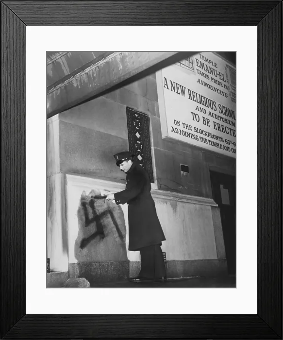 Framed Print : New York City policeman inspects a black swastika painted on the entrance wall of Temple Emanu-el, January 1960