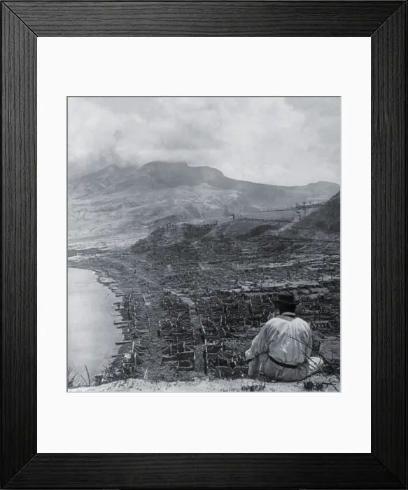 Framed Print : Man on Orange Hill looks over the dead city of St. Pierre, and up to steaming volcano, Mont Pelee. A pyroclastic flow killed 30, 000 people in the coastal city on June 8, 1902